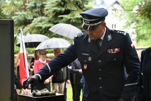 Komendant Powiatowy Policji w Brzesku trzymający w ręku kamień