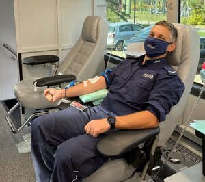 policjant w maseczce zasłaniającej usta i nos podczas oddawania krwi