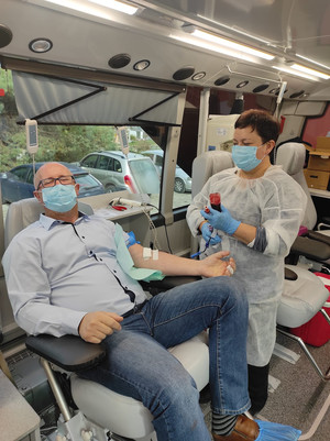 mężczyzna siedzący na fotelu przy nim pielęgniarka w ręku trzymająca oddaną krew