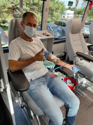 mężczyzna siedzący na fotelu z kciukiem uniesionym do góry w trakcie oddawania krwi