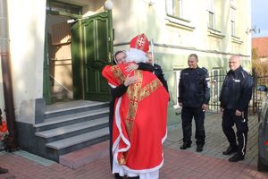 święty Mikołaj witający się z siostrą zakonną, obok stojący policjanci