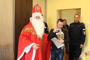 mikołaj obejmujący chłopca, w tle policjanci