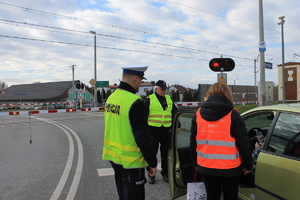 pracownik PKP wręczający ulotkę kierowcy, obok policjant i funkcjonariusz straży ochrony kolei