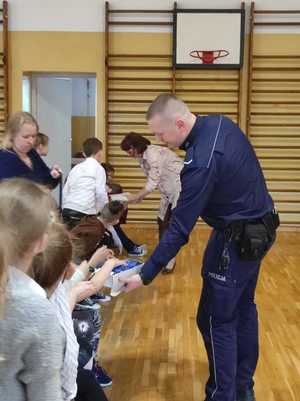 policjant rozdający odblaski uczniom