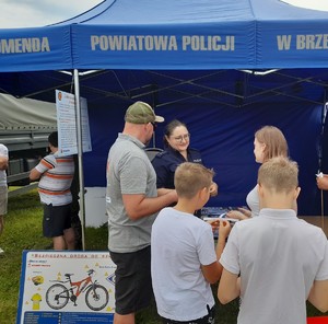 policjantka stojąca przed namiotem z grupą osób biorących udział w konkursie profilaktycznym