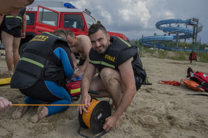 policjant-strażak ochotnik zwijający linę do holowania osoby poszkodowanej