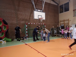 policjanci wręczający nagrody dla grupy dzieci na sali gimnastycznej