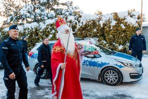 święty mikołaj w towarzystwie policjantów stoi przed budynkiem domu pomocy społecznej