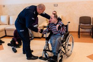 komendant powiatowy policji w Brzesku wita się z chłopcem siedzącym na wózku inwalidzkim