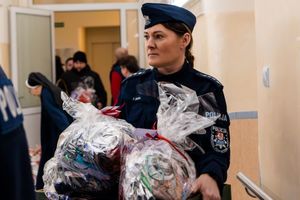 policjantka niosąca w rękach prezenty dla podopiecznych domu pomocy społecznej