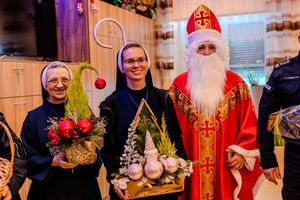 siostry zakonne trzymające w rękach stroiki świąteczne pozujące do zdjęcia z mikołajem